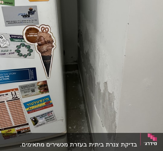 קיר עם קילופי צבע ליד מקרר, סימני רטיבות
